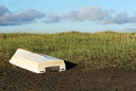 A single white boat lying upside down on the beach, sand, dunes and clear skiesの写真素材