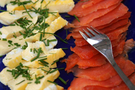 whipped fried eggs with smoked salmin on a deep blue dish ready to be served at a dinner partyの写真素材