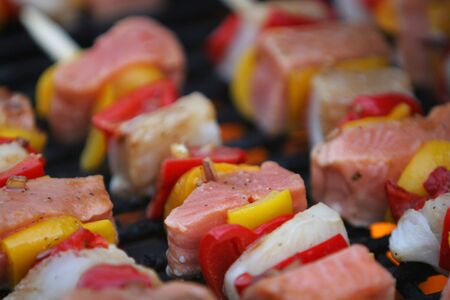 fresh fish on grilling sticks, salmon and halibut with red and yellow pepper being barbecued, very delicious lookingの写真素材