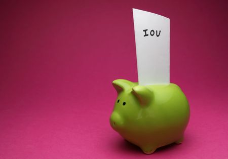 A green piggy bank on pink background, shot slightly from the side with an IOU note in itの写真素材