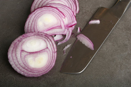 Red onion slices and stainless steel knife