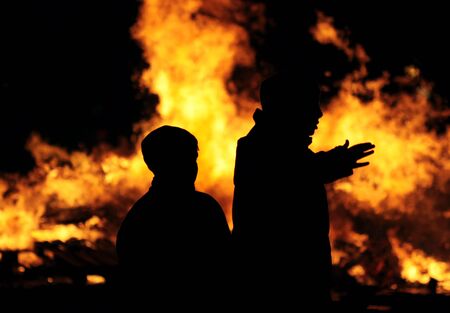 silhouette of two people set against a burning fireの写真素材