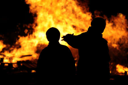 silhouettes set against fire pointing towards itの写真素材