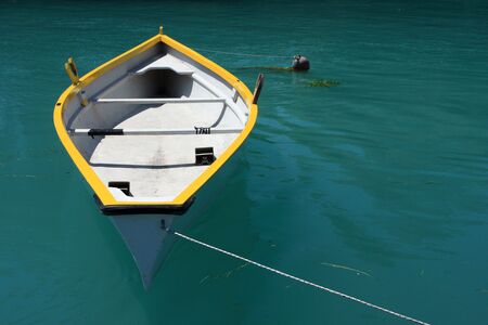 A yellow and white rowing boat on deep green water, plenty of copy spaceの写真素材