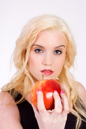 Pretty blond woman holding a red apple looking at camera shot on whiteの写真素材