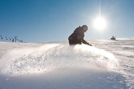 Young man snowboarding in sunshine and perfect weatherの写真素材