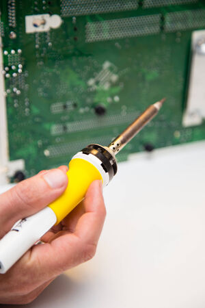 man doing repairs on a circuit board with a soldering ironの写真素材