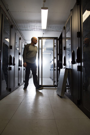 Motion blurred computer specialist walking in a server room installing new equipment, bright light...