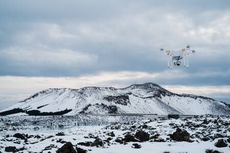 Quadcopter drone being used to photograph and take video at a touirst destination in winter, tourists in the backgroundの写真素材