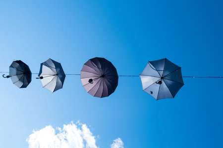 Umbrellas on a wire set against a blue sky