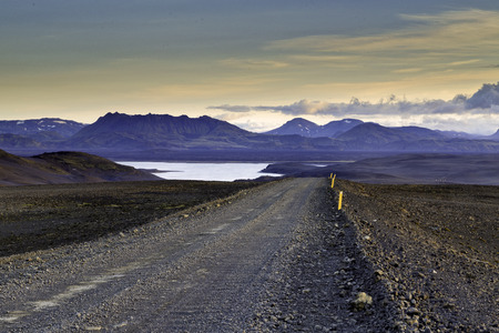 Rural gravel road shot in golden hour leading towards distant mountainsの写真素材