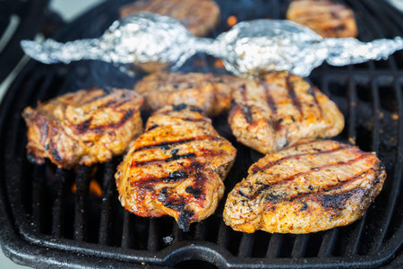 Porkchops on the grill, flames and smoke rising up, meat is just about ready