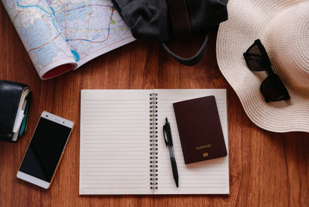Notebook and travel accessories costumes on wood table background with text space.の写真素材