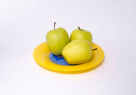 ripe apples on a yellow plateの写真素材