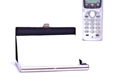 Business card in metal card holder and silver phone isolated on whiteの写真素材