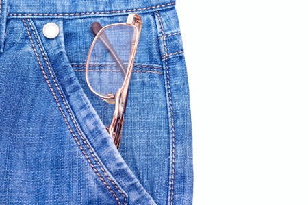 Old gold glasses in blue jeans pocket. Isolated on whiteの写真素材