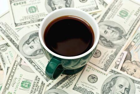 Green cup of coffee on money isolated on whiteの写真素材