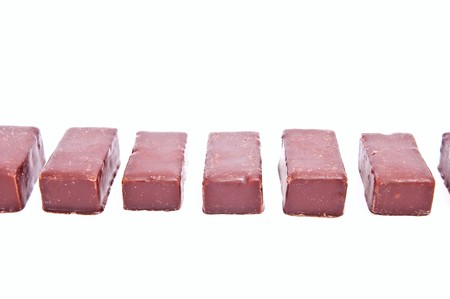 One row from chocolate candies isolated on white backgroundの写真素材