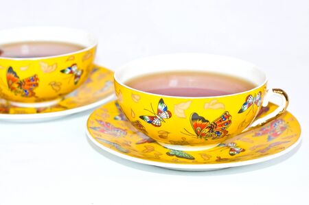 Two yellow cups of tea with butterfliesの写真素材