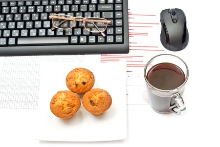 Business still-life with diagrams, glasses, coffee, cake and keyboardの写真素材