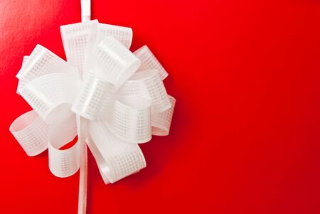 Greeting card with white bow on red backgroundの写真素材