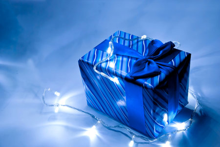 Blue gift box with ribbon and garland . Studio shot