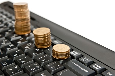 Line of coins on black computer keyboard. Isolated on whiteの写真素材