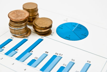 Stack of coins on a blue business chart. Focus on chart