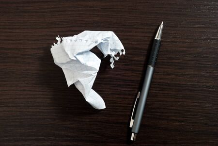Ripped white paper and pen on dark wooden tableの写真素材
