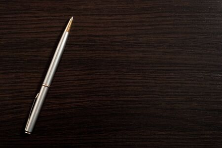 One silver pen on dark wood deskの写真素材