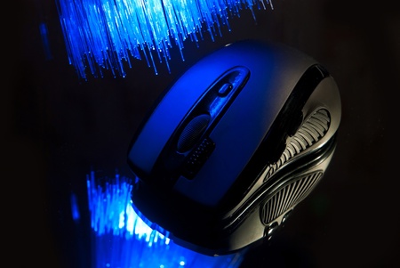 Black wireless pc mouse on glass with fiber optics background.の写真素材