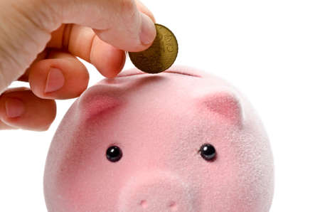 Male hand putting coin into a piggy bankの写真素材