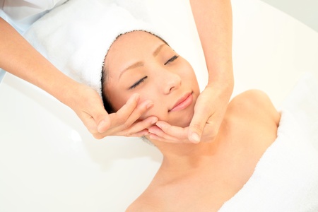 Beautiful young woman receiving facial massageの写真素材