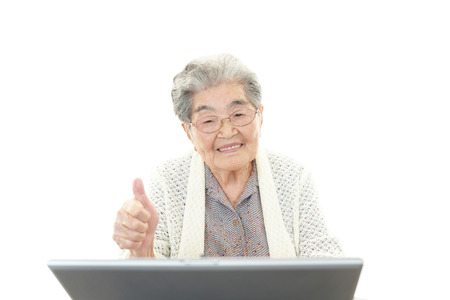 Old woman enjoys computerの写真素材
