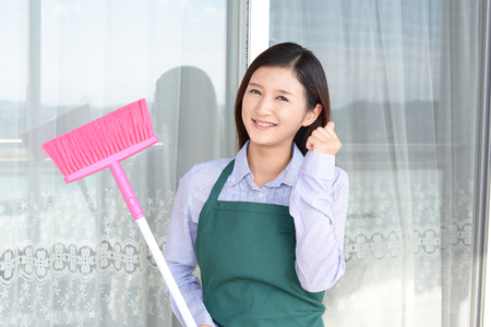 Smiling Asian housewife with a broomの写真素材