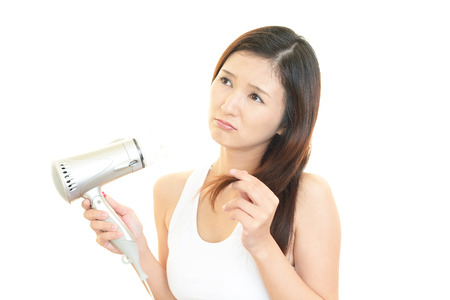 Woman holding split ends of her hair and frownの写真素材