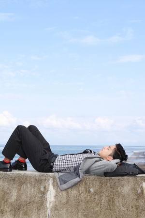 Man lying down on seawallの写真素材