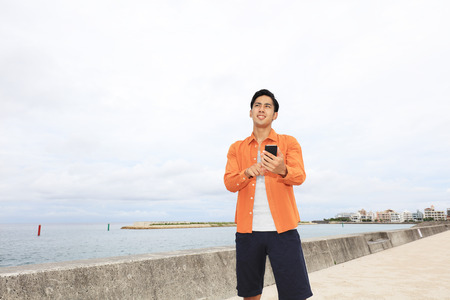 Smiling Asian man by the seaの写真素材