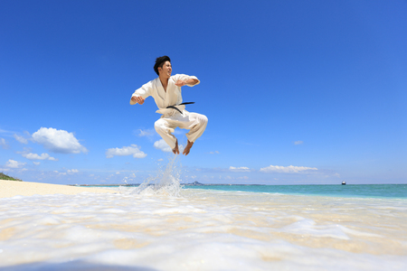 Young adult man with black belt practicing a Kata on the beach on a sunny day.の写真素材