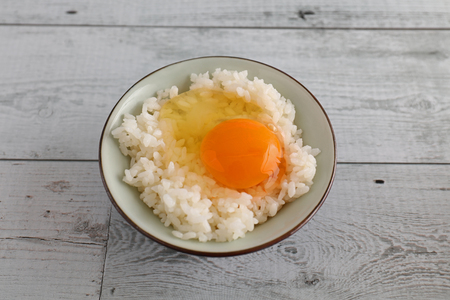 Raw egg on rice in a bowlの写真素材