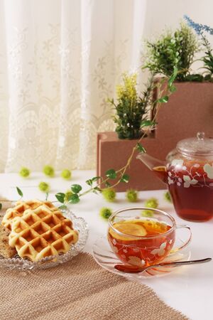 A cup of tea and sweets on the tableの写真素材