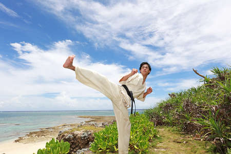 Young man with black belt practicing a Kata on the beach.の写真素材