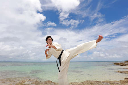 Young man with black belt practicing a Kata on the beach.の写真素材