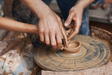 Potter teaches to sculpt in clay pot on a turning pottery wheelの写真素材