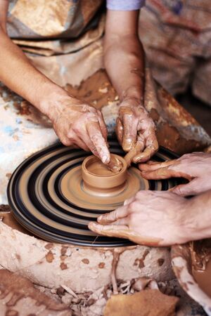 Potter teaches to sculpt in clay pot on a turning pottery wheelの写真素材