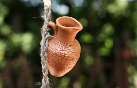 An earthen pot hanging on a rope on a background of green leaves
の写真素材