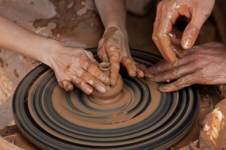 Potter teaches to sculpt in clay pot on the turning pottery wheelの写真素材
