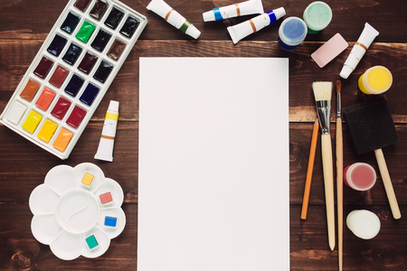 Set of painting equipment with empty paper sheet on wooden tableの写真素材