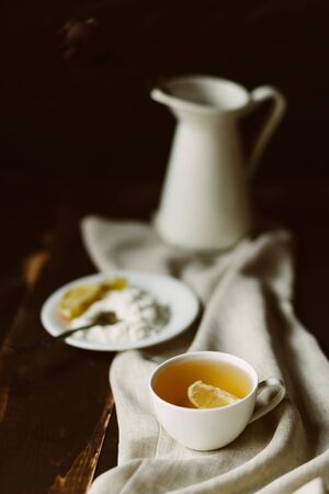 Cup of black tea with lemon and breakfast on wooden table with vaseの写真素材