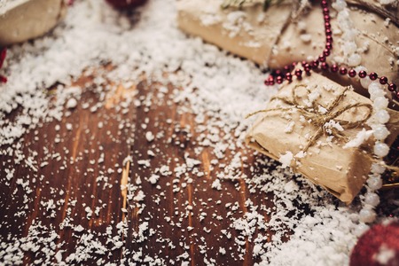 Gift packed in craft paper with snow on wooden tableの写真素材